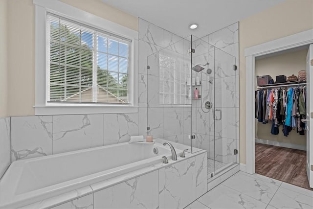 bathroom featuring a marble finish shower, a garden tub, marble finish floor, and a spacious closet