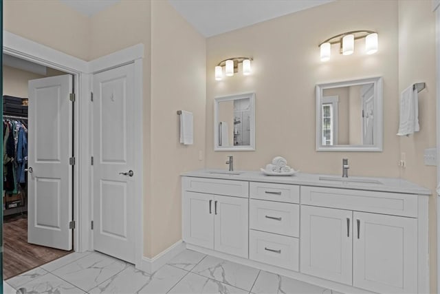 full bathroom featuring double vanity, a sink, marble finish floor, and baseboards