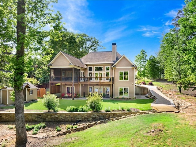 back of house with a lawn, a chimney, an outdoor structure, and a sunroom