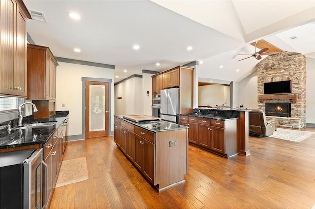 kitchen featuring a kitchen island, open floor plan, ceiling fan, lofted ceiling with beams, and stainless steel appliances