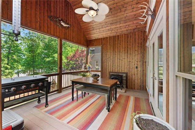 sunroom / solarium with french doors, a ceiling fan, and a wood stove