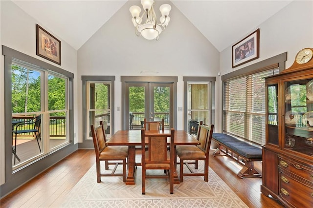 dining room with a chandelier, light wood-type flooring, plenty of natural light, and high vaulted ceiling