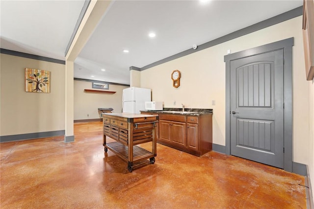 interior space with finished concrete floors, dark countertops, brown cabinetry, white appliances, and recessed lighting