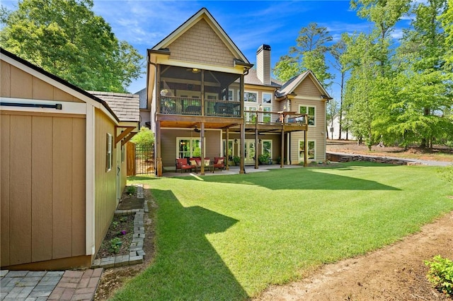 back of property with ceiling fan, a chimney, a sunroom, a patio area, and a yard