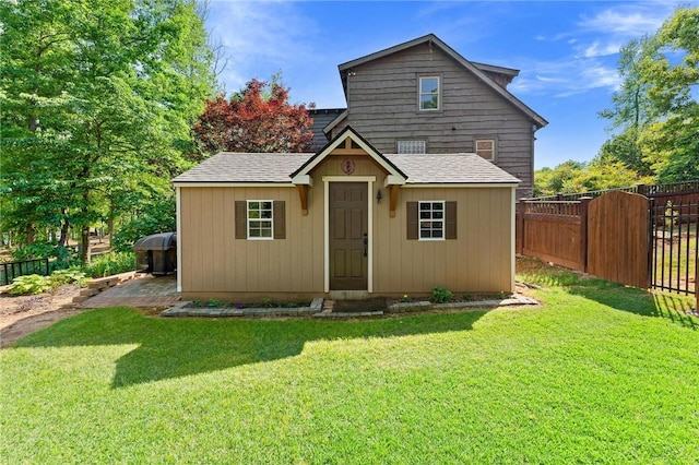 view of front facade with fence, a shingled roof, and a front yard