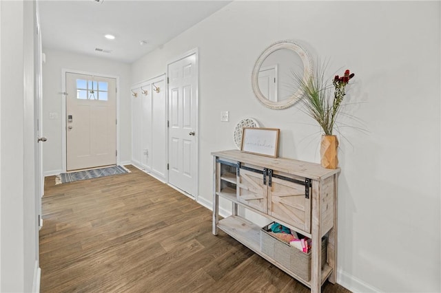 entryway with baseboards, visible vents, and wood finished floors