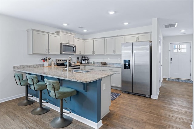kitchen featuring visible vents, a sink, a kitchen breakfast bar, a peninsula, and stainless steel appliances