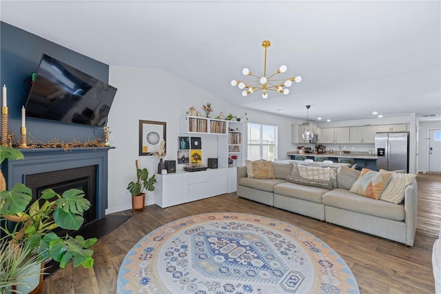 living area with an inviting chandelier, a fireplace, dark wood-style floors, vaulted ceiling, and recessed lighting