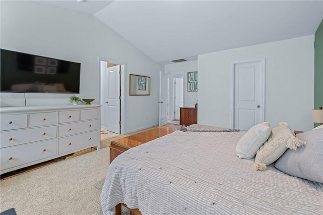 bedroom featuring baseboards, light wood-style floors, visible vents, and vaulted ceiling