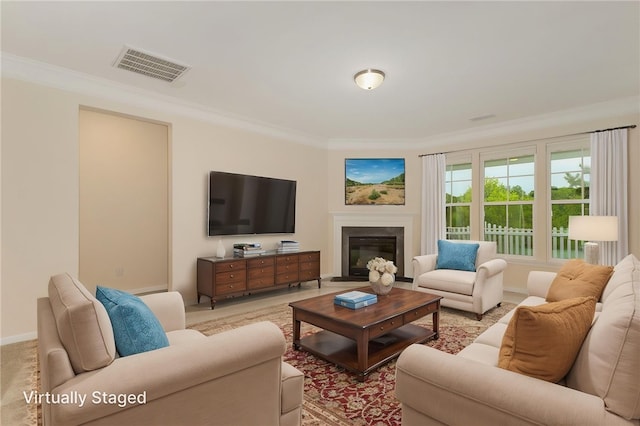 living room featuring ornamental molding, a glass covered fireplace, and baseboards