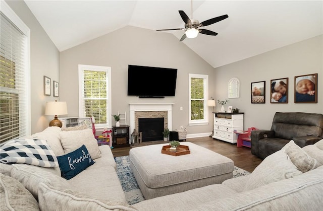 living room with a stone fireplace, wood finished floors, ceiling fan, and vaulted ceiling