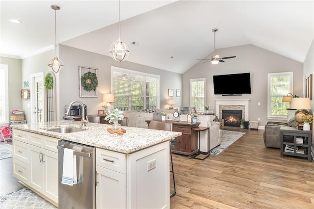 kitchen with a sink, dishwasher, light wood-style flooring, open floor plan, and white cabinets