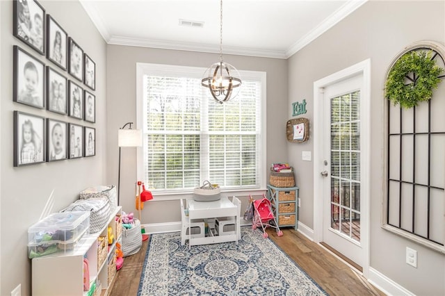 game room featuring baseboards, ornamental molding, an inviting chandelier, and wood finished floors