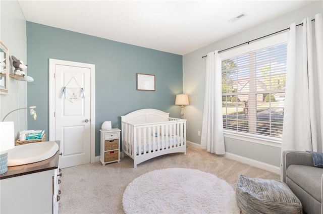 bedroom featuring baseboards, carpet flooring, visible vents, and a crib