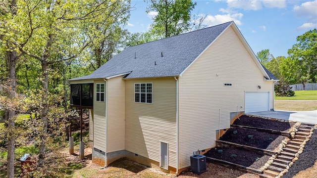 view of side of home with a garage, a sunroom, crawl space, concrete driveway, and central AC unit
