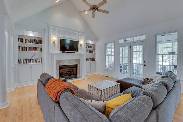 living room featuring a ceiling fan, a premium fireplace, built in features, high vaulted ceiling, and light wood-style floors