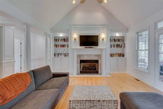 living room with wood finished floors, visible vents, a fireplace, and built in shelves