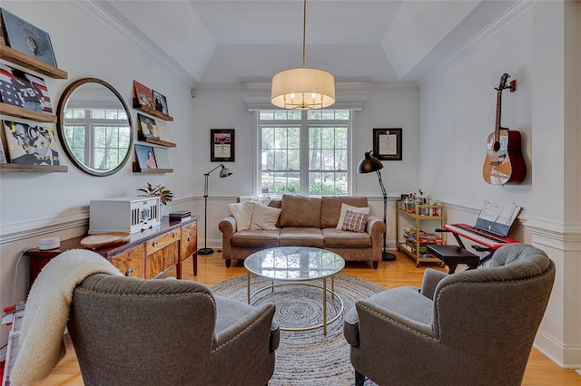 living area featuring a raised ceiling, light wood-style floors, crown molding, and a notable chandelier