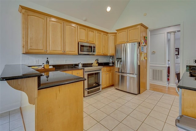 kitchen featuring light tile patterned floors, stainless steel appliances, a peninsula, and tasteful backsplash