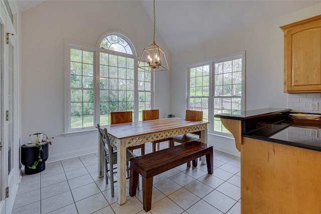 dining room featuring light tile patterned floors, baseboards, an inviting chandelier, and vaulted ceiling