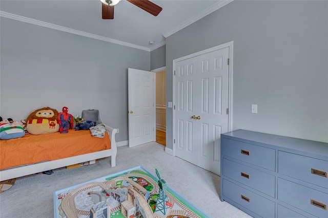 bedroom featuring a ceiling fan, a closet, baseboards, crown molding, and light colored carpet