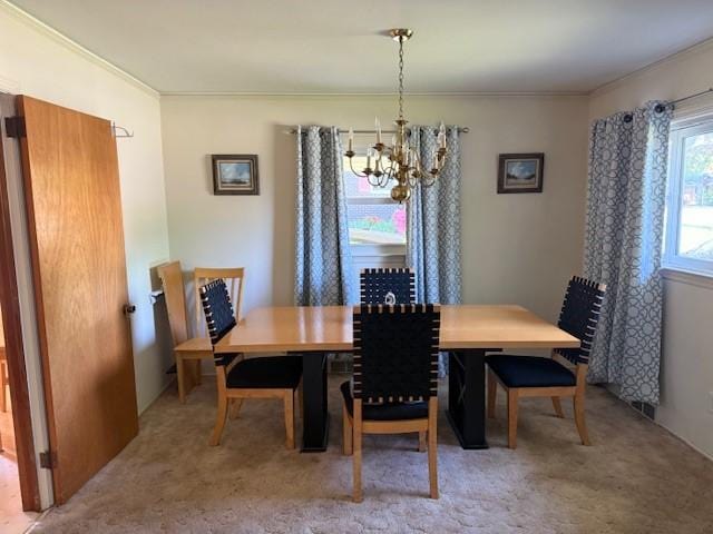 dining room with a notable chandelier, crown molding, and light colored carpet