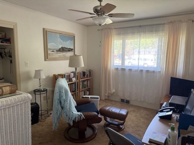 living area with a ceiling fan, visible vents, and carpet