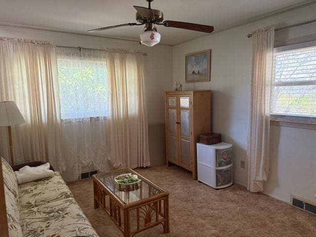 living area with ceiling fan, visible vents, and light colored carpet
