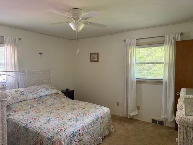bedroom featuring ceiling fan, light carpet, and visible vents