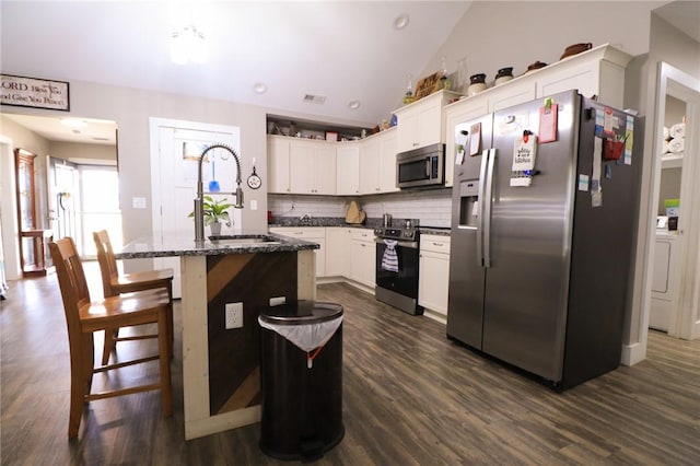 kitchen featuring a sink, dark wood-style flooring, backsplash, appliances with stainless steel finishes, and lofted ceiling