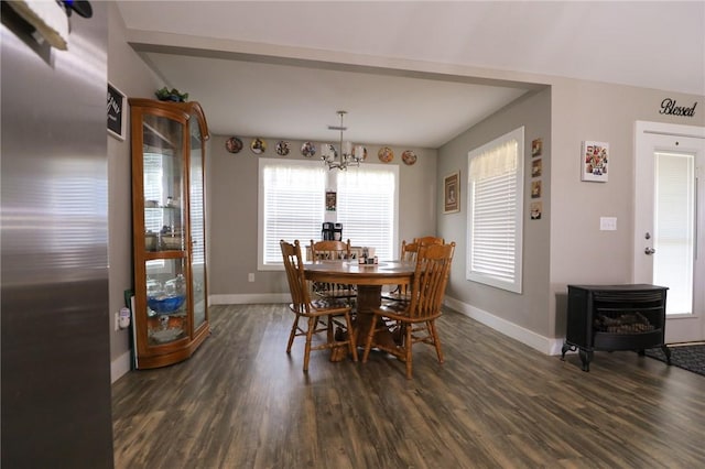 dining room with a wood stove, baseboards, and dark wood-style floors