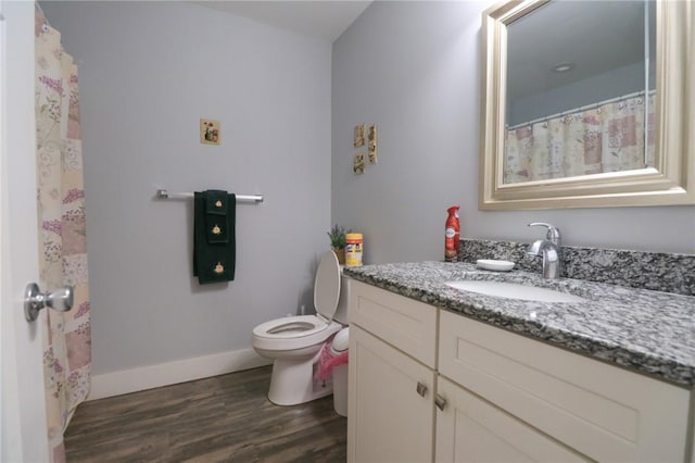 bathroom featuring toilet, baseboards, vanity, and wood finished floors