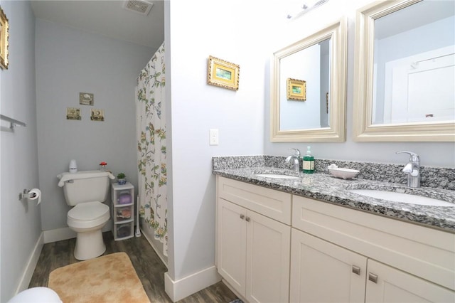 bathroom with toilet, visible vents, a sink, and wood finished floors