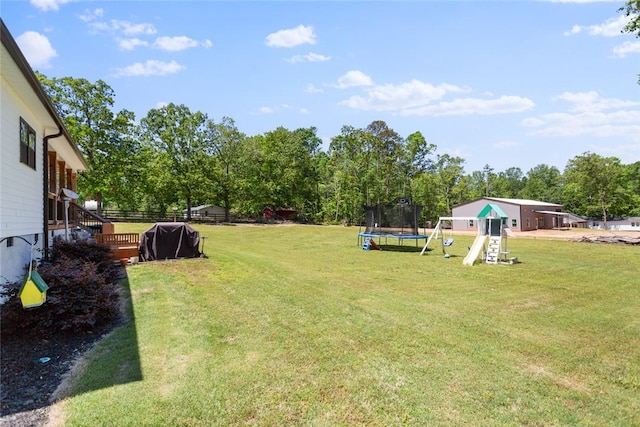 view of yard with a trampoline, a playground, and view of wooded area