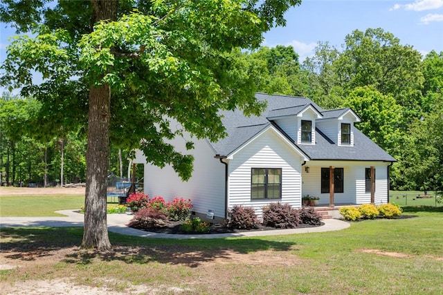 view of front of house featuring covered porch, a front yard, and a shingled roof