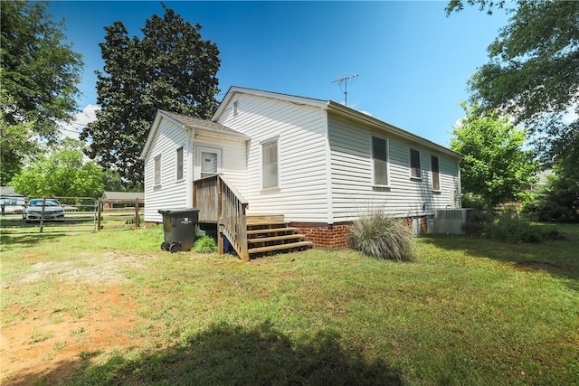 view of side of home featuring central AC unit, fence, and a lawn