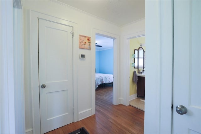 hallway featuring crown molding, baseboards, and wood finished floors