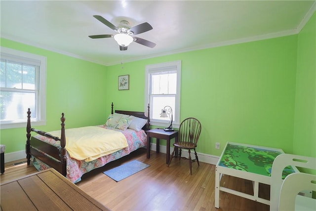 bedroom with baseboards, crown molding, and wood finished floors