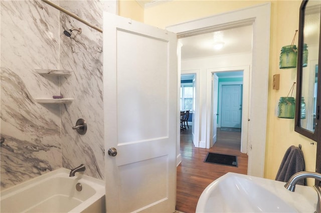 bathroom with tub / shower combination, wood finished floors, a sink, crown molding, and visible vents