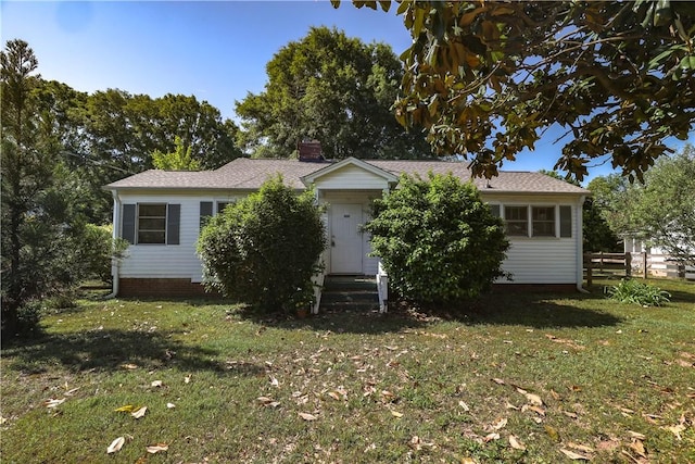view of front facade featuring a front lawn, a shingled roof, a chimney, and entry steps