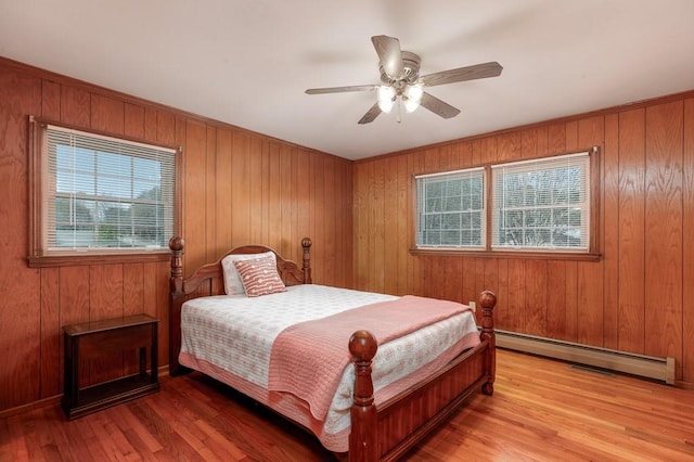 102 Norman St, Liberty, SC 29657 - bedroom with a baseboard heating unit, multiple windows, wood walls, and light wood-type flooring