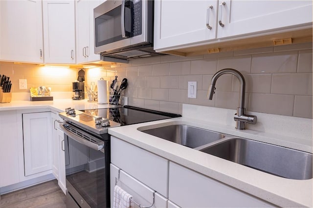 kitchen with white cabinets, stainless steel microwave, a sink, and range with electric cooktop