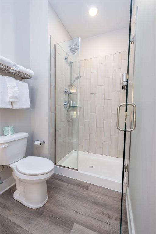 bathroom featuring a stall shower, toilet, and wood finished floors