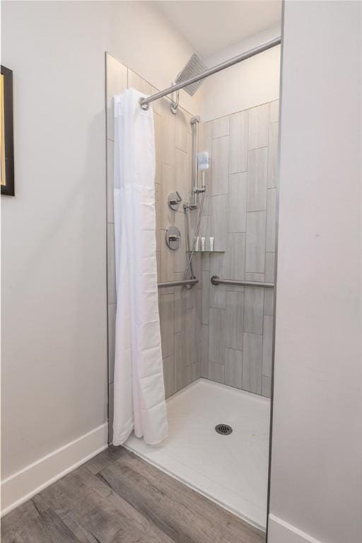 full bathroom with baseboards, tiled shower, and wood finished floors