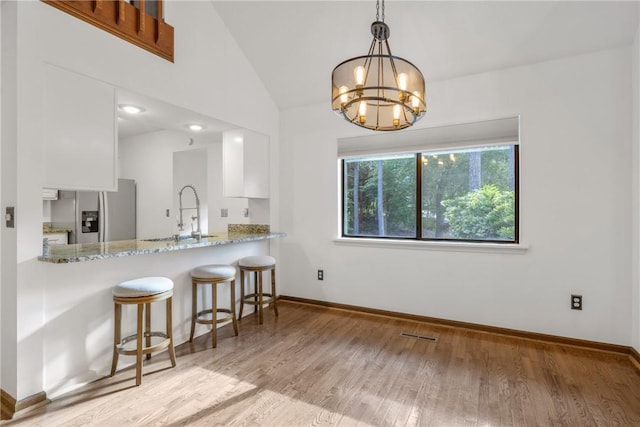 110 Safe Harbor Cir, Salem, SC 29676 - kitchen with stainless steel refrigerator with ice dispenser, a sink, white cabinetry, wood finished floors, and a chandelier