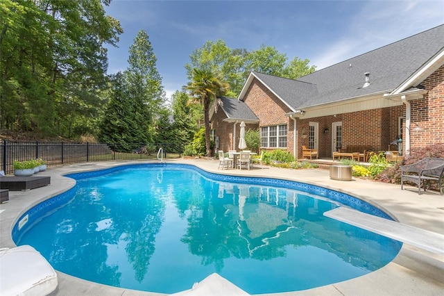 view of pool featuring a patio area, fence, and a diving board