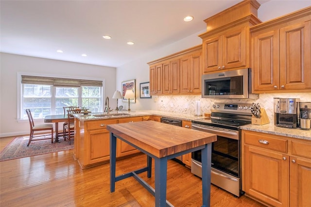 kitchen with appliances with stainless steel finishes, a sink, a peninsula, tasteful backsplash, and recessed lighting