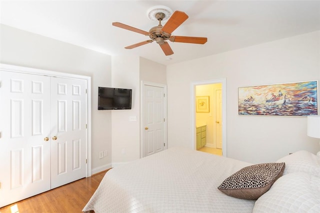 bedroom featuring light wood finished floors, a closet, a ceiling fan, baseboards, and ensuite bath