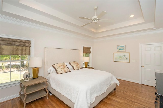 bedroom with a tray ceiling, light wood-style flooring, baseboards, recessed lighting, and ceiling fan