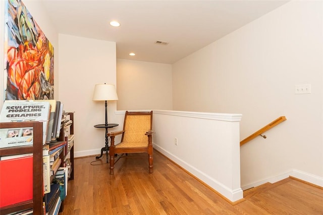 living area with an upstairs landing, wood finished floors, baseboards, and recessed lighting